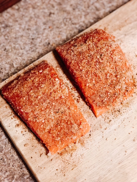 two raw filet of salmon with seasonings rubbed on them 