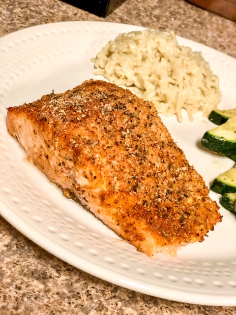 cooked salmon filet on a white plate with side of zucchini and rice 