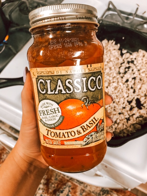 hand holding a jar of Classico tomato & basil sauce 