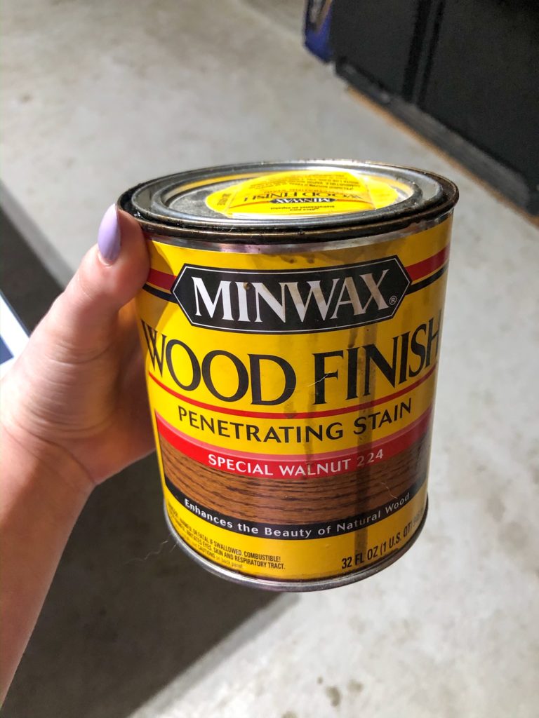 hand holding minwax special walnut wood stain after whitewash