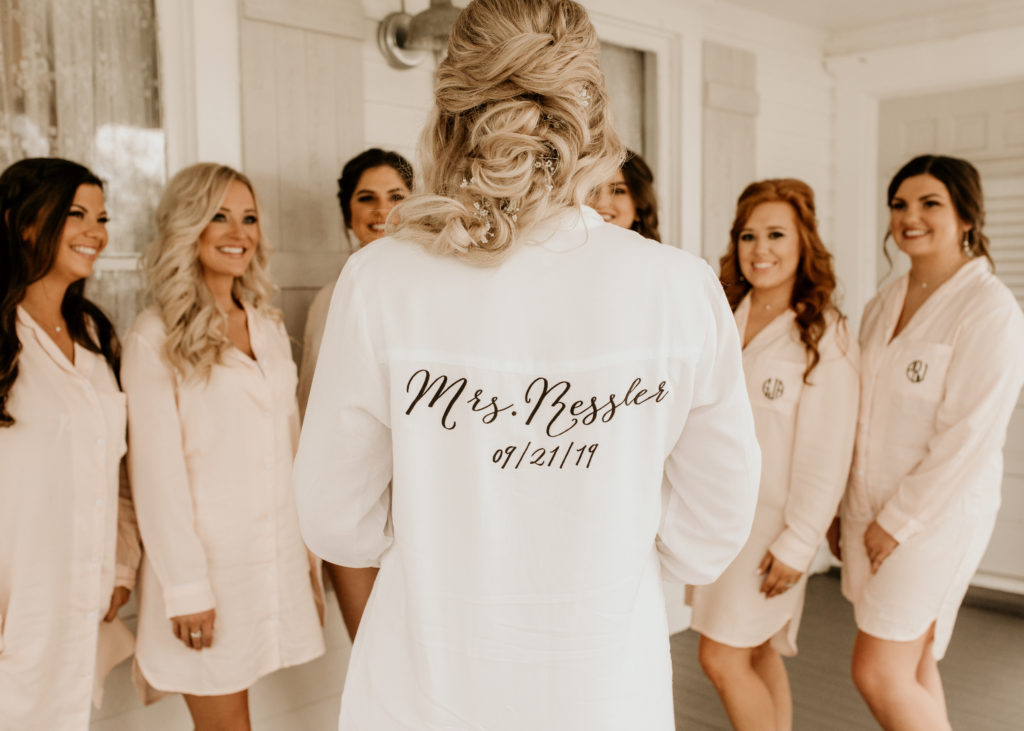 Woman wearing white sleep shirt with her name written on the back and a group of girls behind her in matching outfits