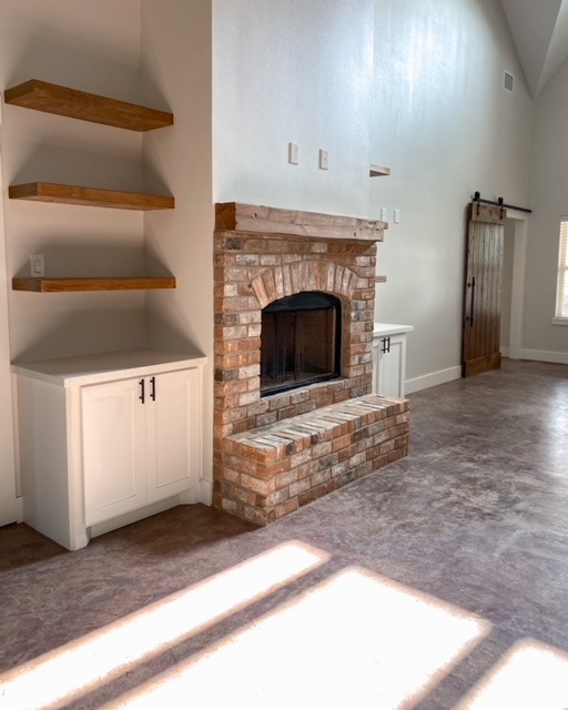 stained concrete floors with a fireplace and wood open shelving